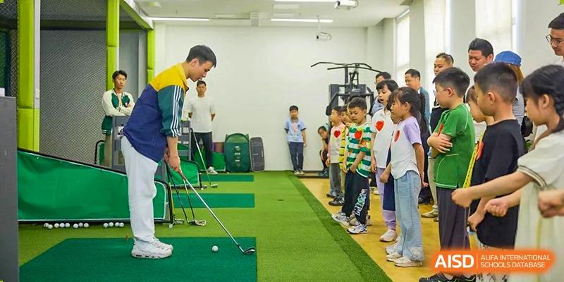 A line of students receiving instruction and practicing putting at an indoor golf training area at Wuxi Kuangyuan Bilingual School.