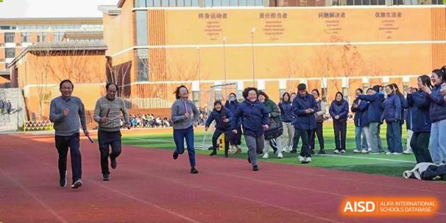 A group of students running on a track during an outdoor sports day or physical education class at Wuxi Kuangyuan Bilingual School.