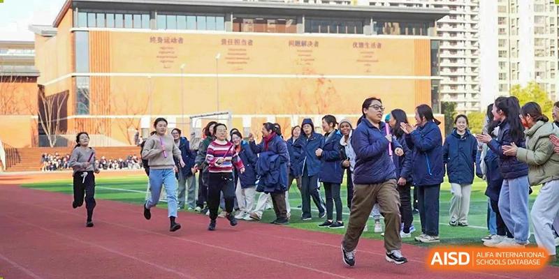 A large group of students in dark blue coats participating in an outdoor sports or team activity at Wuxi Kuangyuan Bilingual School.