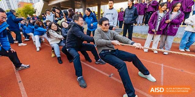 A close-up shot of hands and arms pulling a rope during a tug-of-war competition at Wuxi Kuangyuan Bilingual School.