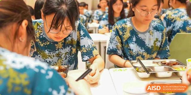Students in patterned uniforms working on a hands-on activity or taking notes at their desks at Wuxi Kuangyuan Bilingual School.