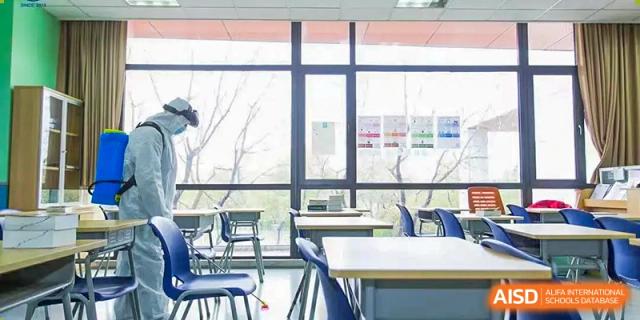 View of a well-lit, empty classroom with large windows overlooking trees at Wuxi United International School.