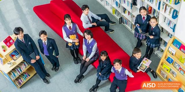 Students sitting on a red tiered reading area in the school library at Wuxi United International School.