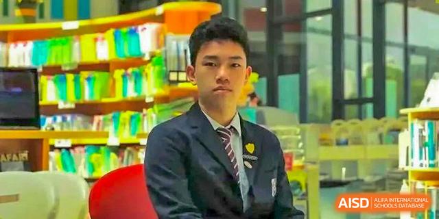 Male student in school uniform with a tie posing seriously for a portrait at Wuxi United International School.
