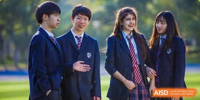 Two students in dark blazers and ties standing outside at Wuxi United International School.