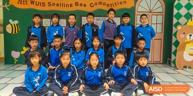 A group of young students sitting in uniform posing for a photo at Wuxi United International School.