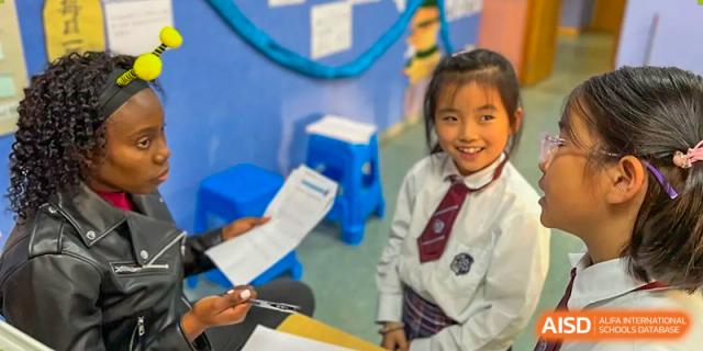A young female student smiling and participating in a classroom activity at Wuxi United International School.