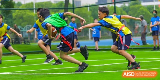 Students playing flag football or tag on a green sports field at Wuxi United International School.