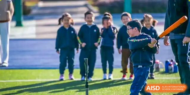 A group of students in dark uniforms posing outdoors on a sports field at Wuxi United International School.