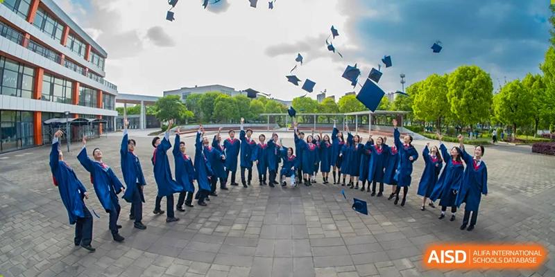 Graduating students in blue gowns throwing their caps into the air at Wuxi United International School.