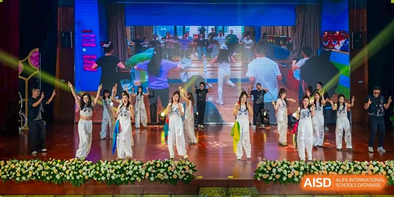 Students performing on a stage in white, bright traditional costumes at Wuxi United International School.