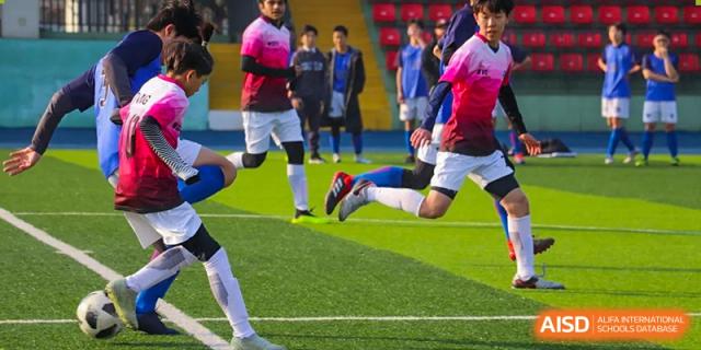 Students playing soccer or football on a green turf field during a match at Wuxi United International School.