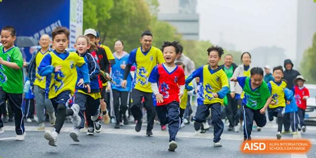 Children running in a group outdoors during a race or fun run activity at Wuxi United International School.