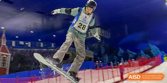 Student in protective gear snowboarding or skiing on an indoor slope at Wuxi United International School.