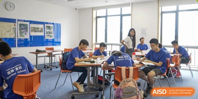 Students from Wycombe Abbey School Nanjing studying in a classroom with a teacher walking in the background.