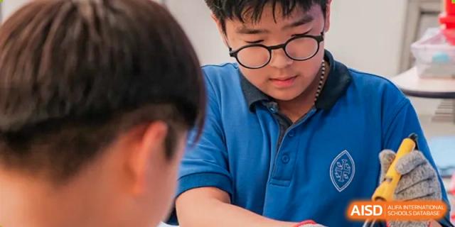 A student from Wycombe Abbey School Nanjing wearing glasses and a blue shirt while focused on a task.