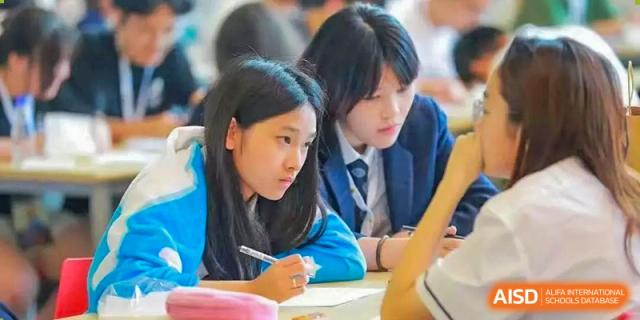 Two students from Wycombe Abbey School Nanjing looking at a book together.