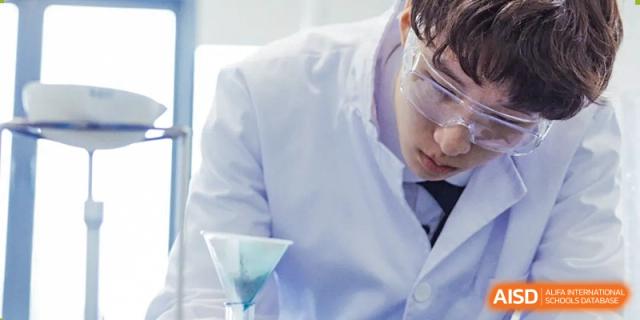 A student from Wycombe Abbey School Nanjing pouring a liquid from a beaker in a lab.