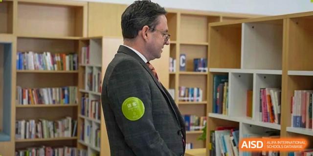 A male teacher from Wycombe Abbey School Nanjing smiling in a library.