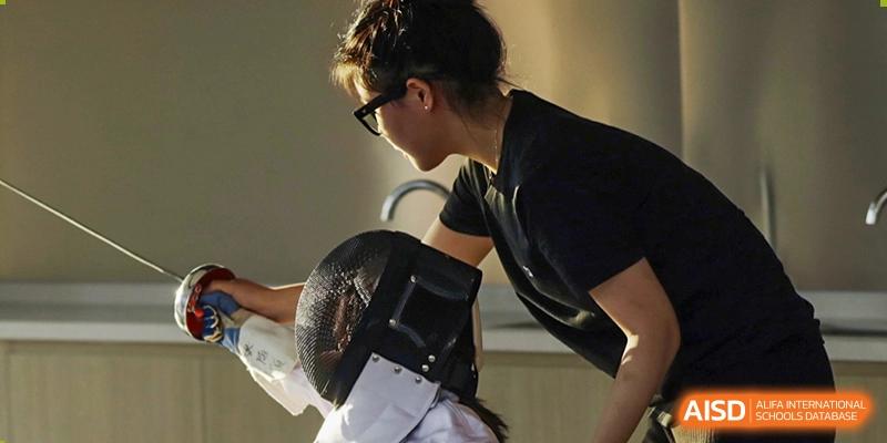 A student from Wycombe Abbey School Nanjing holding a fencing helmet.