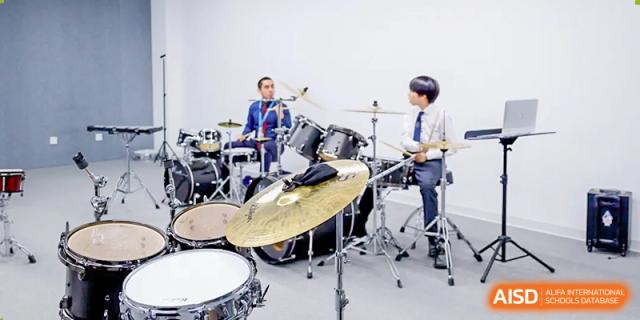Two students from Wycombe Abbey School Nanjing playing the drums and guitar in a band.