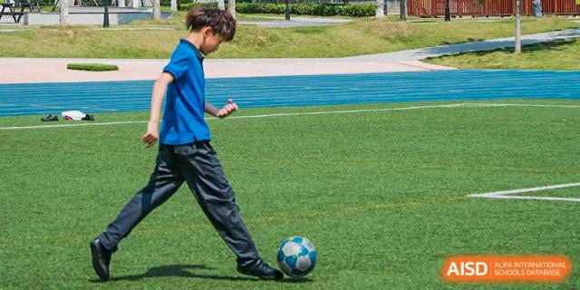 A student from Wycombe Abbey School Nanjing kicking a soccer ball on a track field.