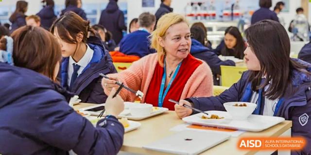 A teacher from Wycombe Abbey School Nanjing eating a meal at a table in the cafeteria.