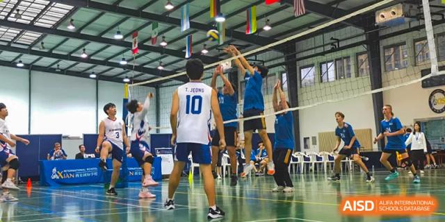 Xi'an International School students playing an intense game of indoor volleyball, with one student wearing a white jersey with the number 10.