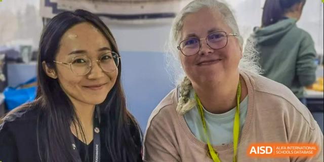 A close-up portrait of an older female staff member or teacher at Xi'an International School, smiling next to a student.