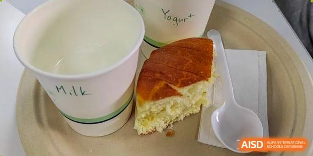 A serving of yogurt and a slice of bread or cake on a tray, labeled "Yogurt," representing a snack or meal at Xi'an International School.