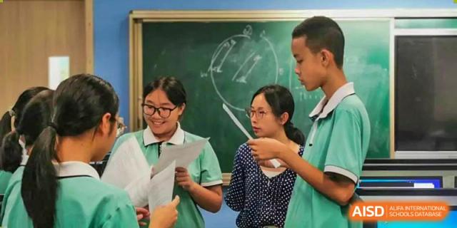 A teacher from Xiamen Yingcai school helping a group of students in a classroom.