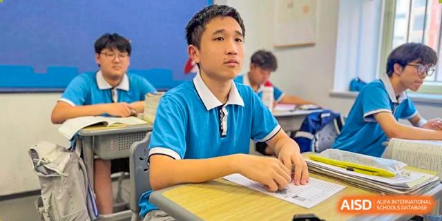 A male student from Xiamen Yingcai school listening attentively to a lecture in a classroom.