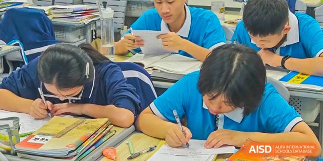 A student from Xiamen Yingcai school writing on paper at a desk.