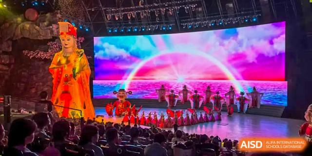 Students from Xiamen Yingcai school performing on a stage with a colorful backdrop.