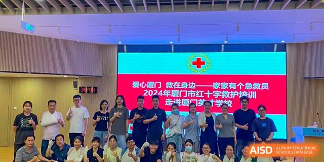Students and teachers from Xiamen Yingcai school posing for a group photo in front of a screen.