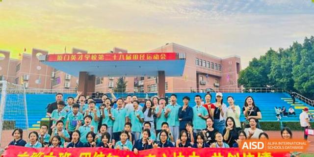 Students and teachers from Xiamen Yingcai school taking a group photo outside the school building.