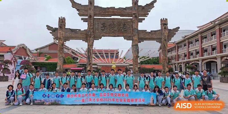 Xiamen Yingcai school students holding a banner in front of a traditional gate at their school.