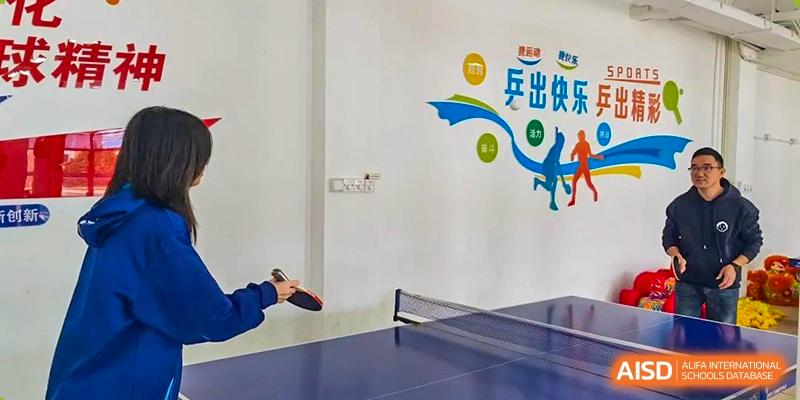 A student from Xiamen Yingcai school playing table tennis in a gym.