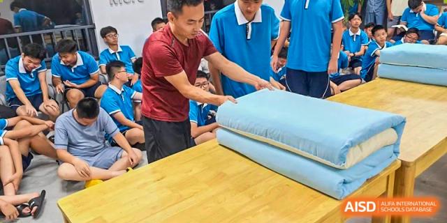 A teacher from Xiamen Yingcai school helping a student with a mattress in a dormitory.