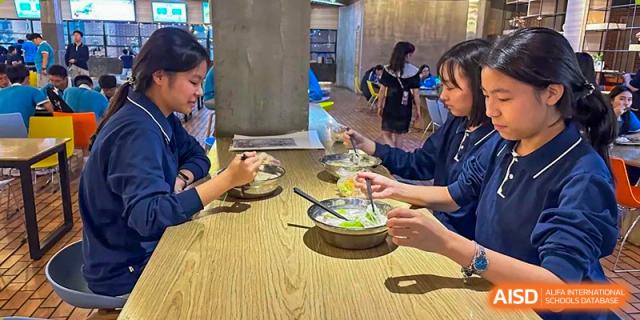 Students from Xiamen Yingcai school eating a meal together at a table.