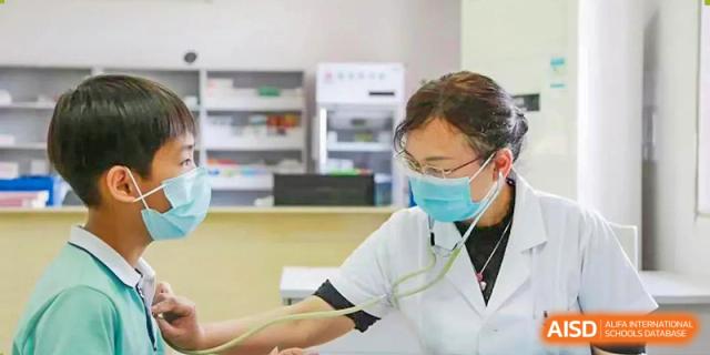 A nurse from Xiamen Yingcai school checking a student's arm in the school clinic.
