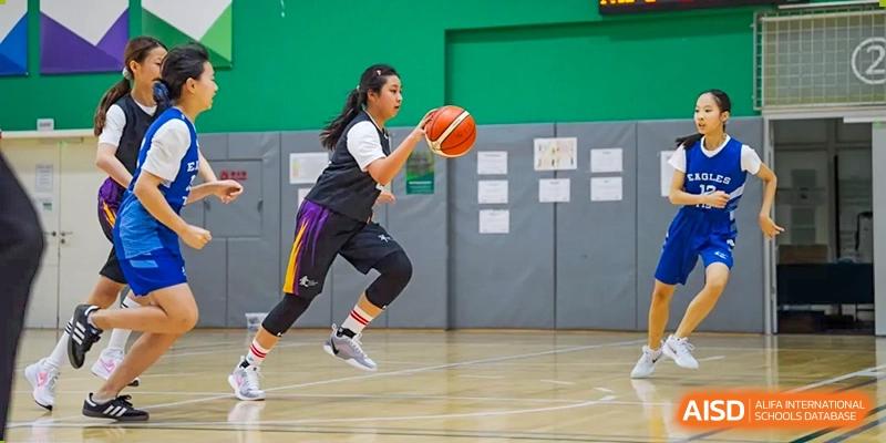 A female student athlete from Yantai Huasheng International School (YHIS) in a purple and black uniform jumping to shoot a basketball during a game or practice.