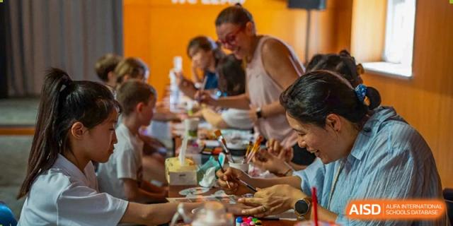 Students and adults from Yantai Huasheng International School (YHIS) participating in a group activity or enjoying a shared meal, with people focused on their plates.