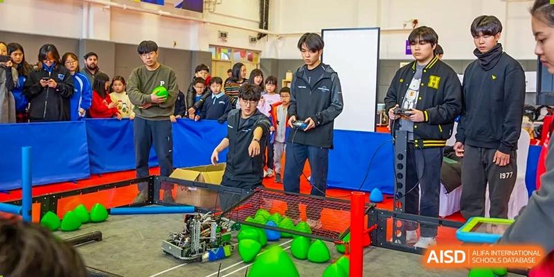 A student from Yantai Huasheng International School (YHIS) working with a robot and bright green balls on a competition field.