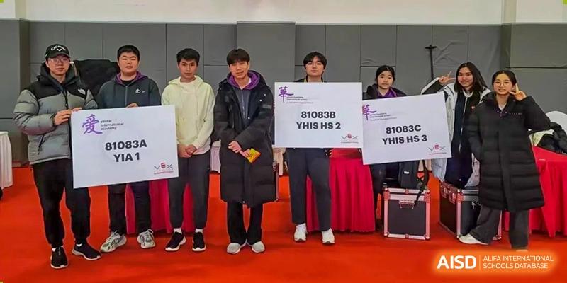 Adults holding signs and standing at an official event or awards ceremony at Yantai Huasheng International School (YHIS).