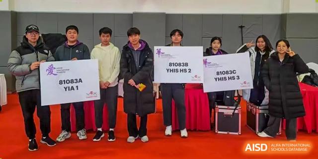 Adults holding signs and standing at an official event or awards ceremony at Yantai Huasheng International School (YHIS).