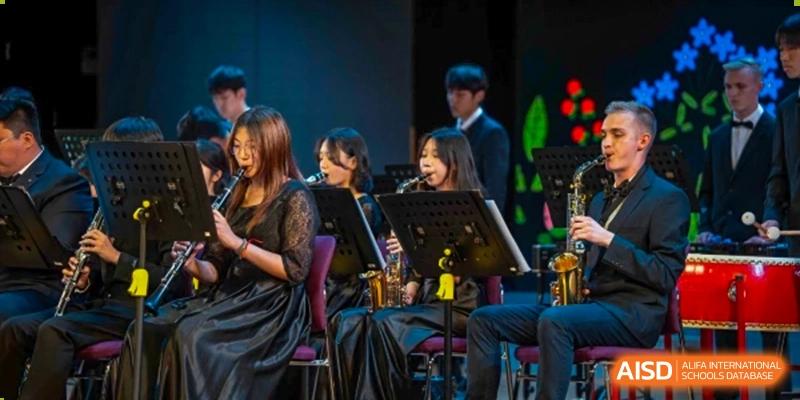 Female students from Yantai Huasheng International School (YHIS) performing music together on stage with instruments like a saxophone and clarinet.