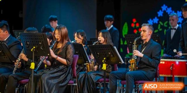 Female students from Yantai Huasheng International School (YHIS) performing music together on stage with instruments like a saxophone and clarinet.
