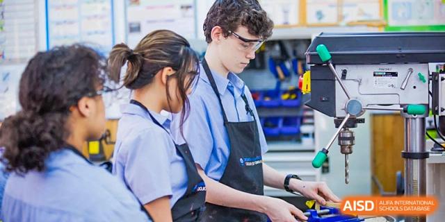 Two students wearing aprons and working on a project in a workshop at Yew Chung International School of Shanghai.