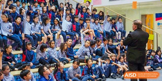 A large group of students sitting on the floor, watching a performance or presentation at Yew Chung International School of Shanghai.